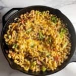 Ham and cheese pasta bake in a black skillet.