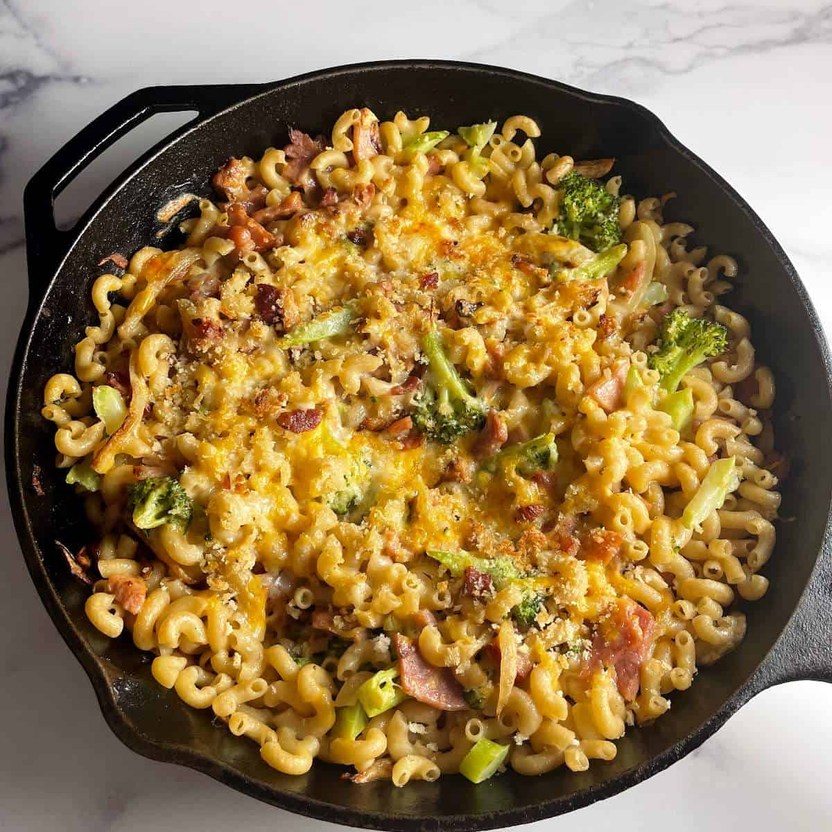 ham and cheese pasta bake in a black skillet.