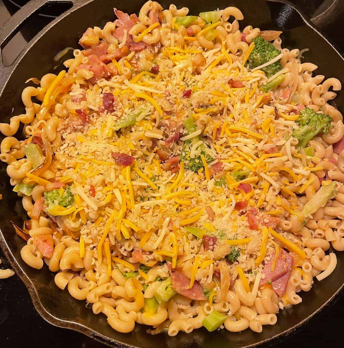 a large black skillet with ham, cheese and pasta ready to back in the oven.