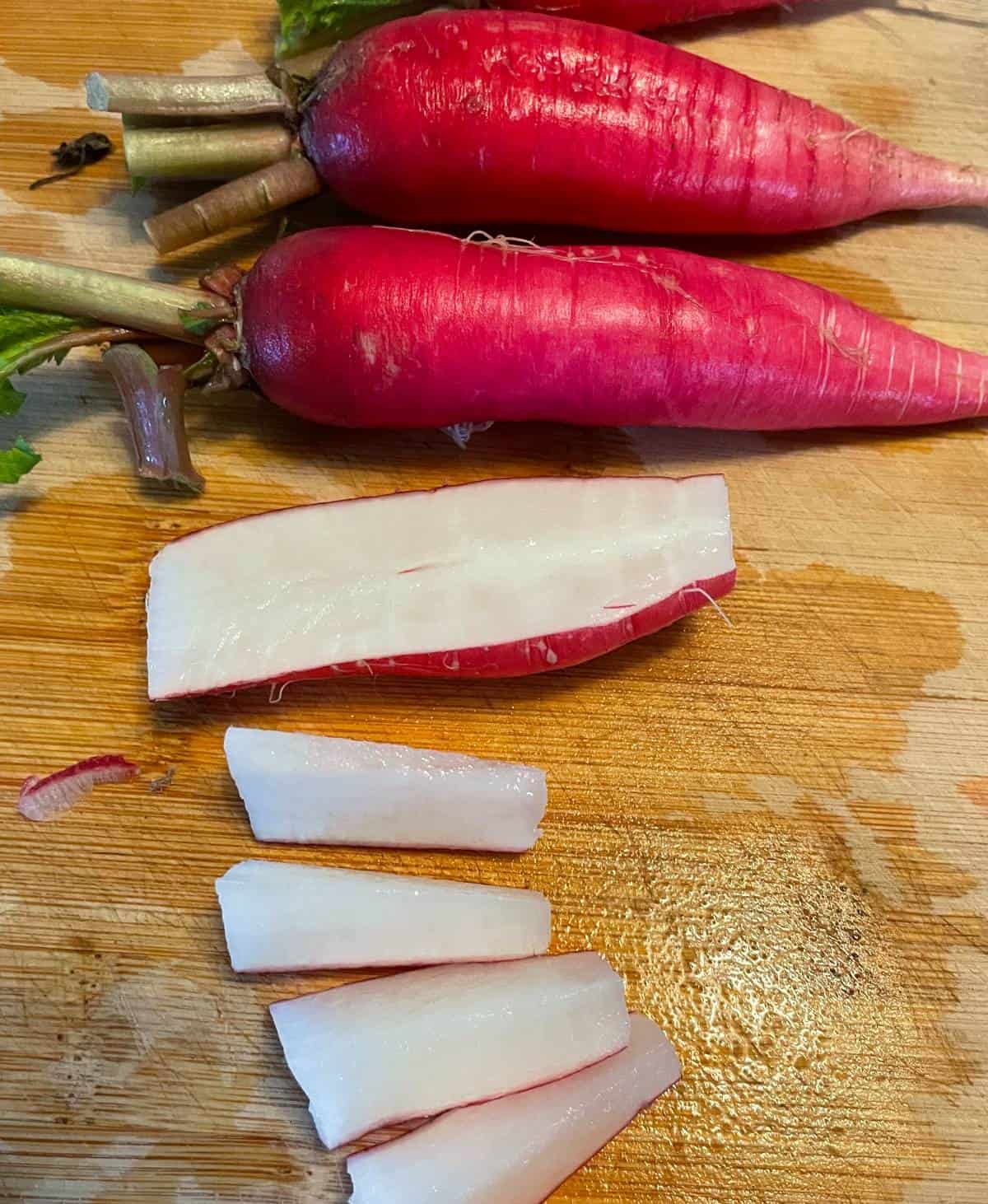 Radishes being chopped on a cutting board, showing the white inside part of the vegetable.