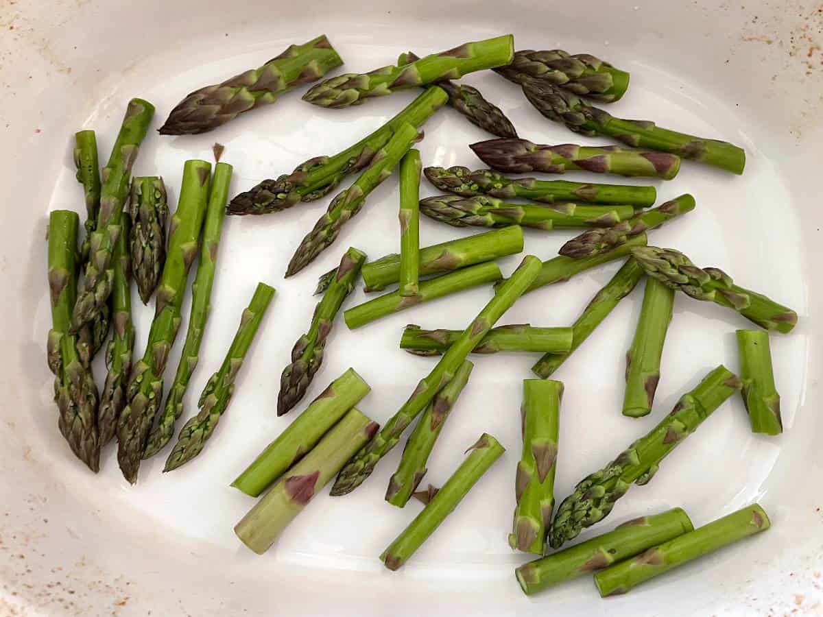 chopped asparagus in a white baking dish prior to baking.