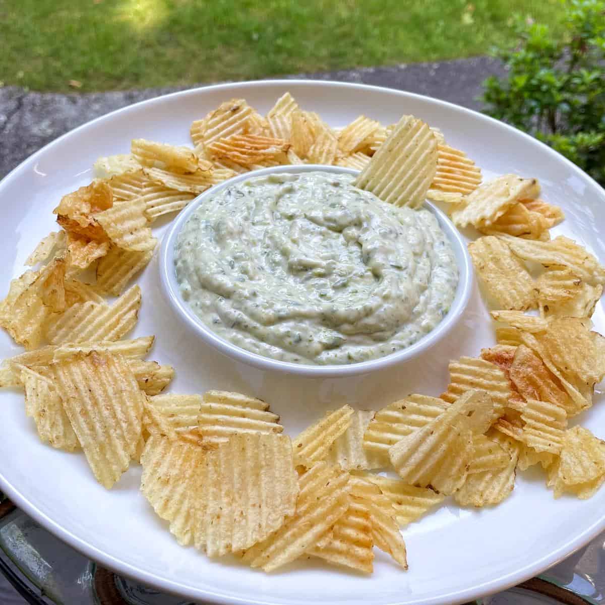 roasted asparagus dip served outside in a dip bowl, along with potato chips.
