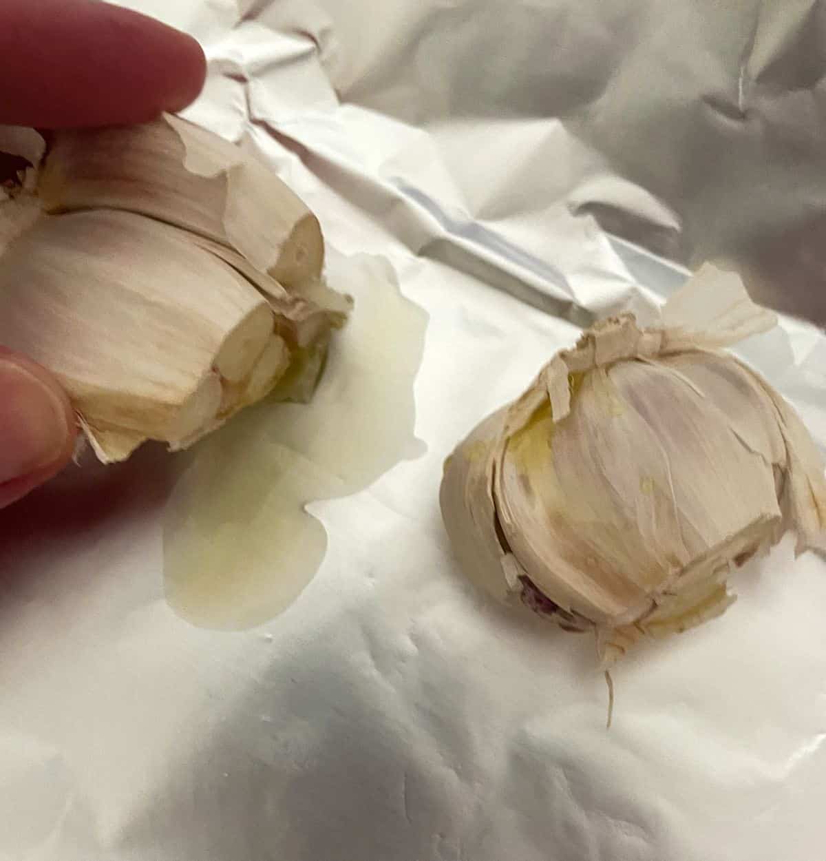 garlic cloves on aluminum foil, with olive oil, prior to roasting.