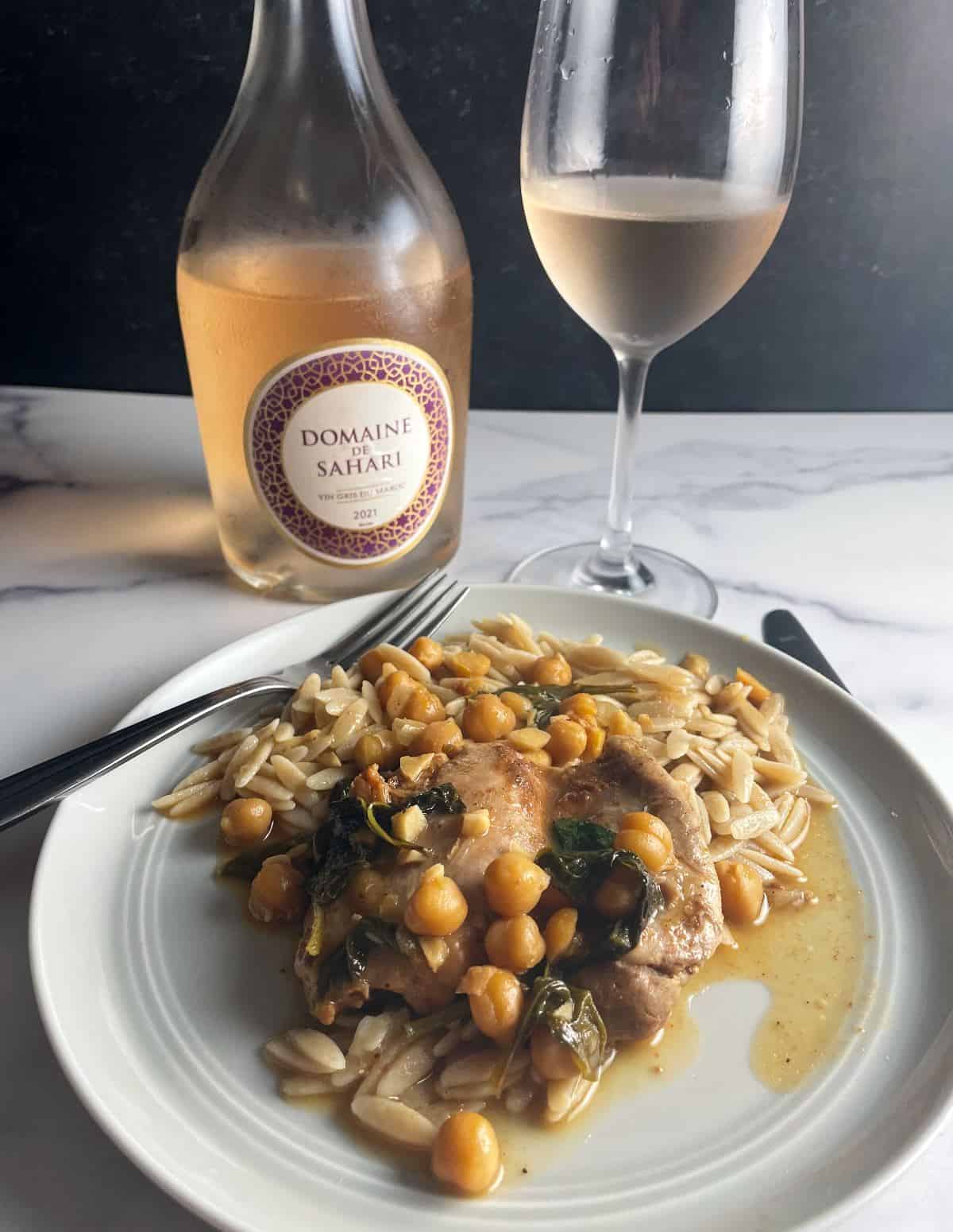 Moroccan chicken thighs and chickpeas plated with orzo and served with a Moroccan rosé wine.