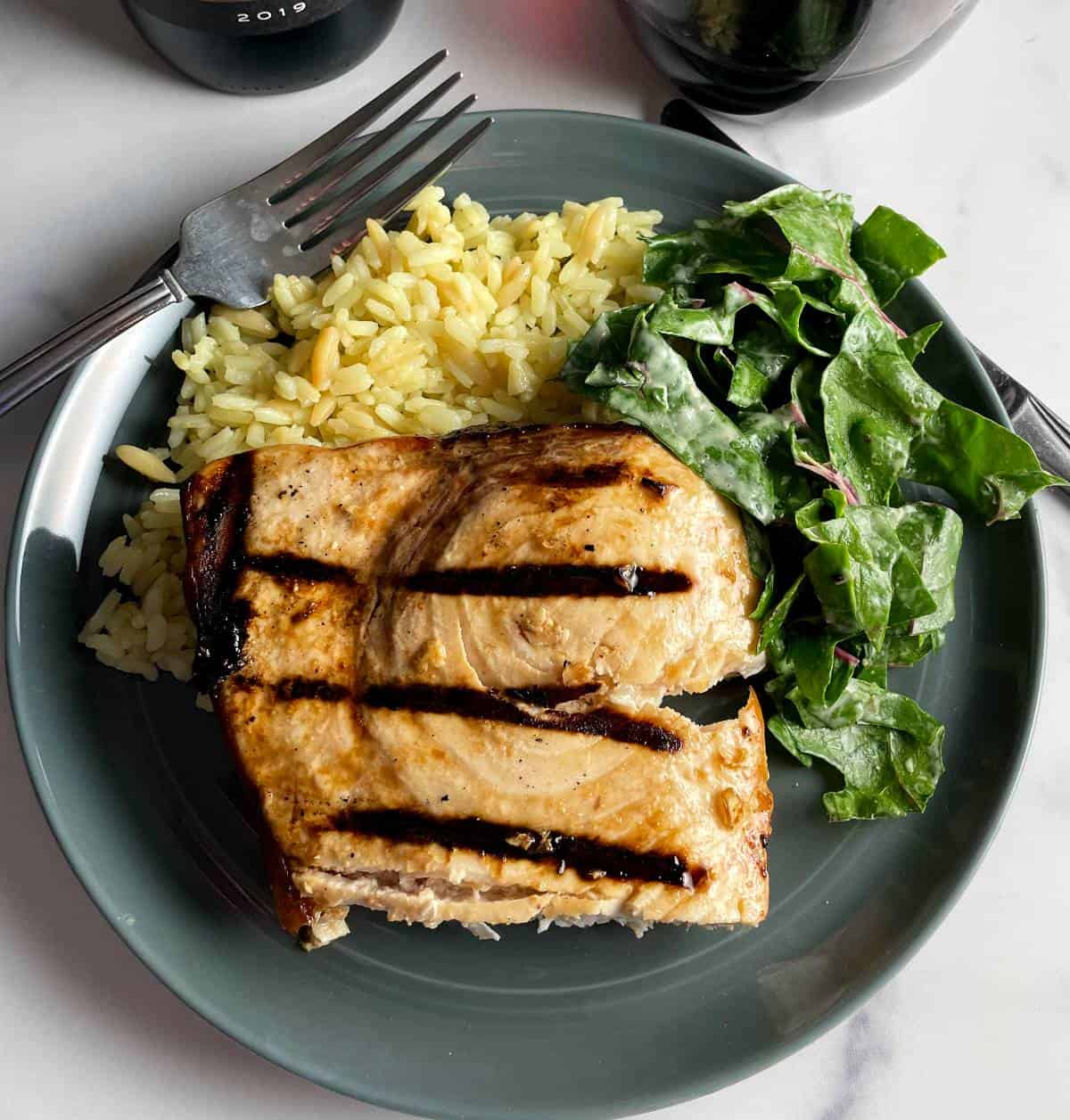 grilled swordfish plated with rice pilaf and a green salad.