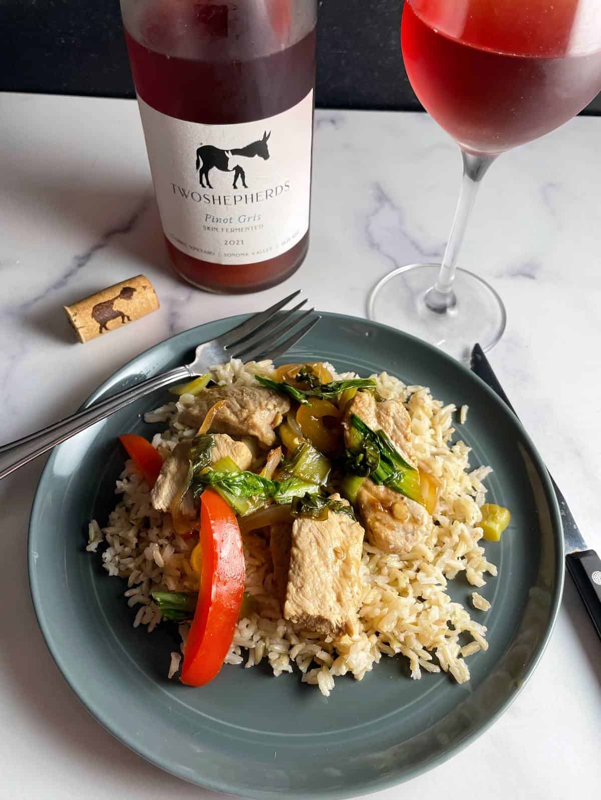 Pork and Bok Choy Stir-Fry served with rice, with a rosé colored wine in the background. 