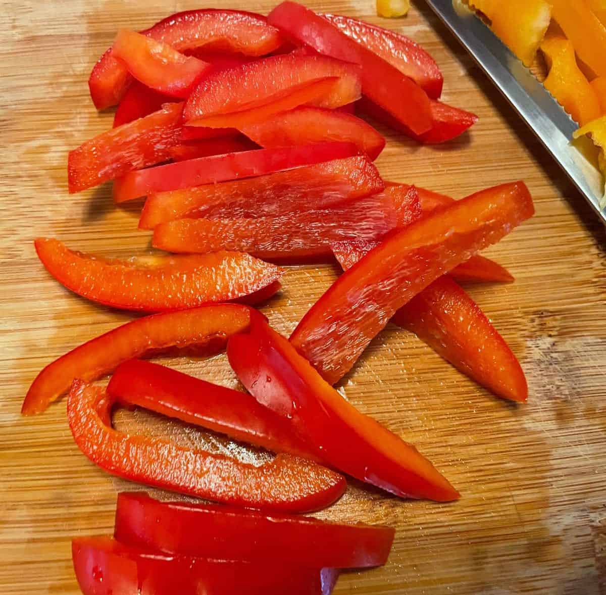 Sliced red peppers on a wood cutting board.