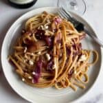 red cabbage tossed with linguine and feta cheese, served on a gray plate.