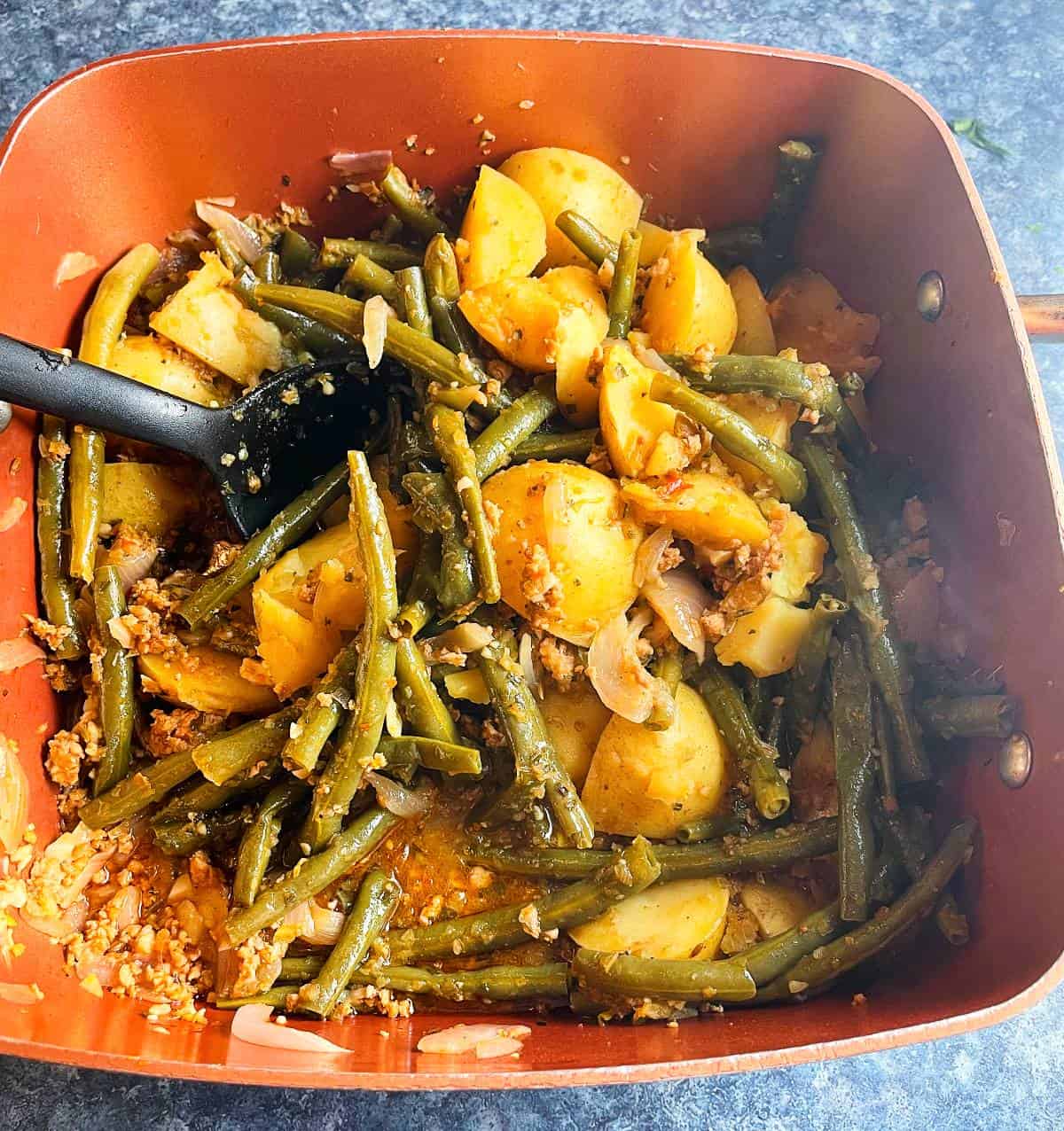 green beans and potatoes cooked in a pan with Andouille sausage. 
