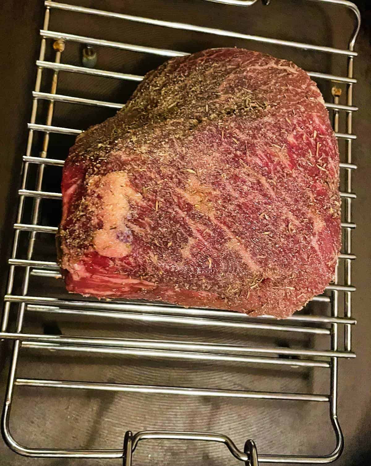top round roast beef, on a roasting rack, prior to being put into the oven.