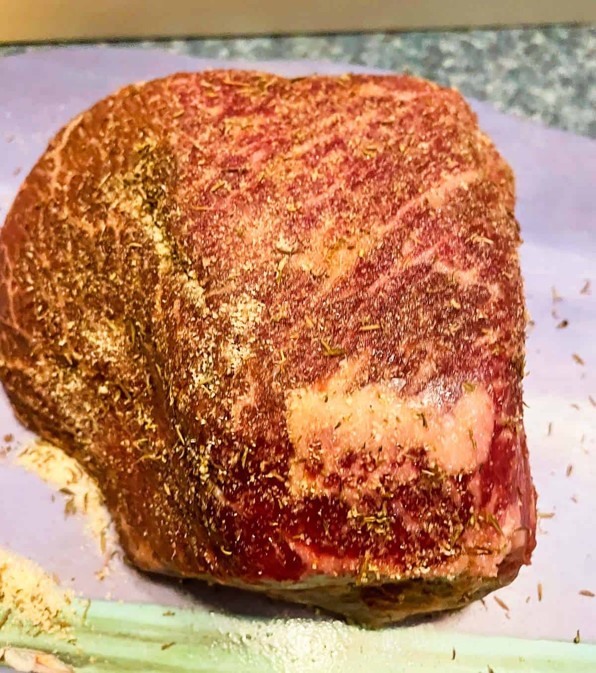 raw top round roast beef with spice rub applied.