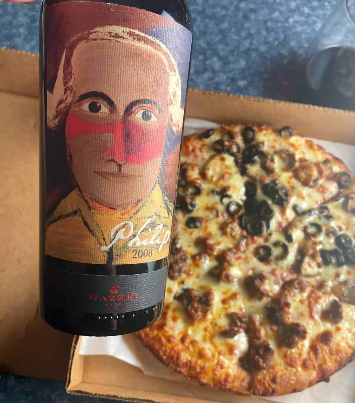 A bottle of 2008 Philip Cabernet Toscana, shown above a box of takeout pizza.