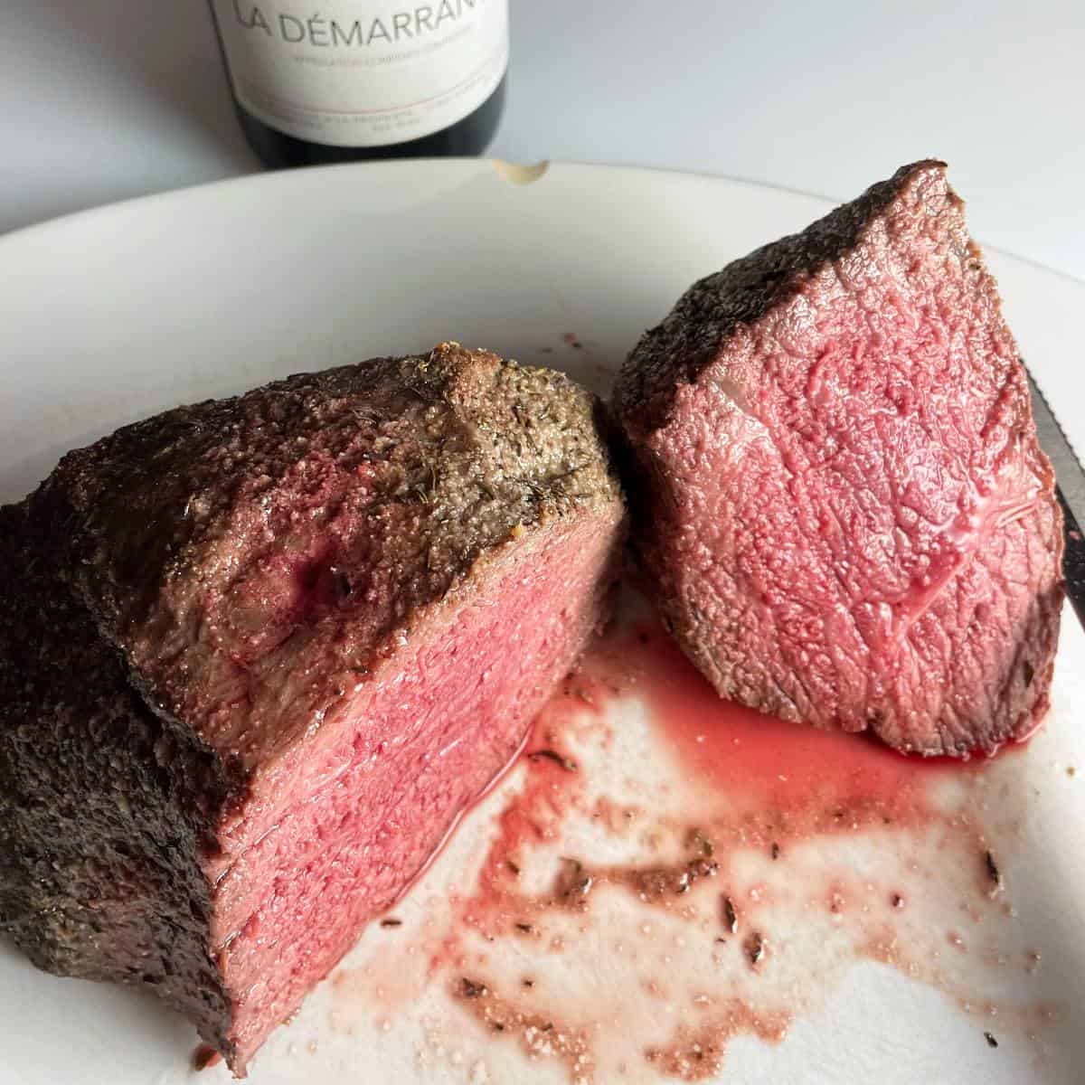 Medium rare top round roast beef, sliced in half, on a white platter.