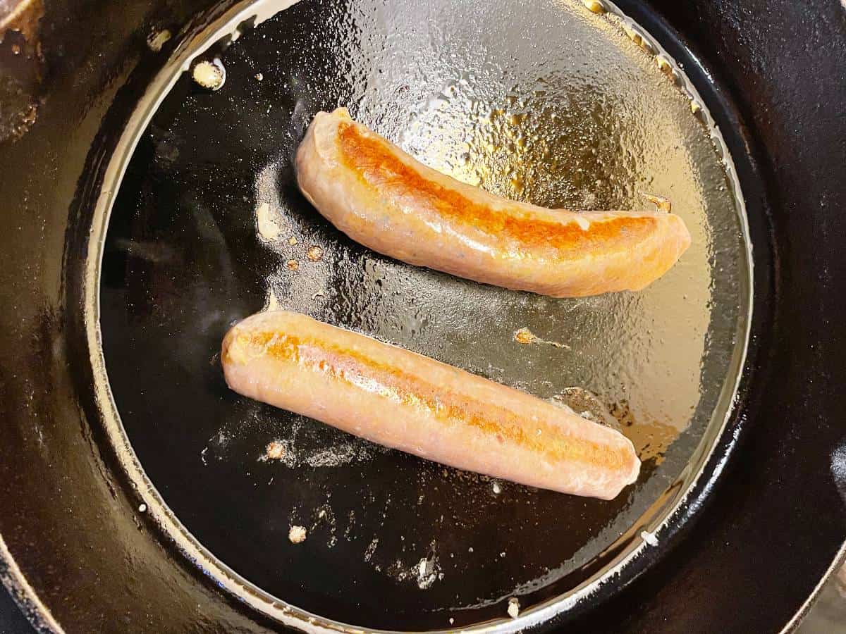 browning sausage in a black skillet.
