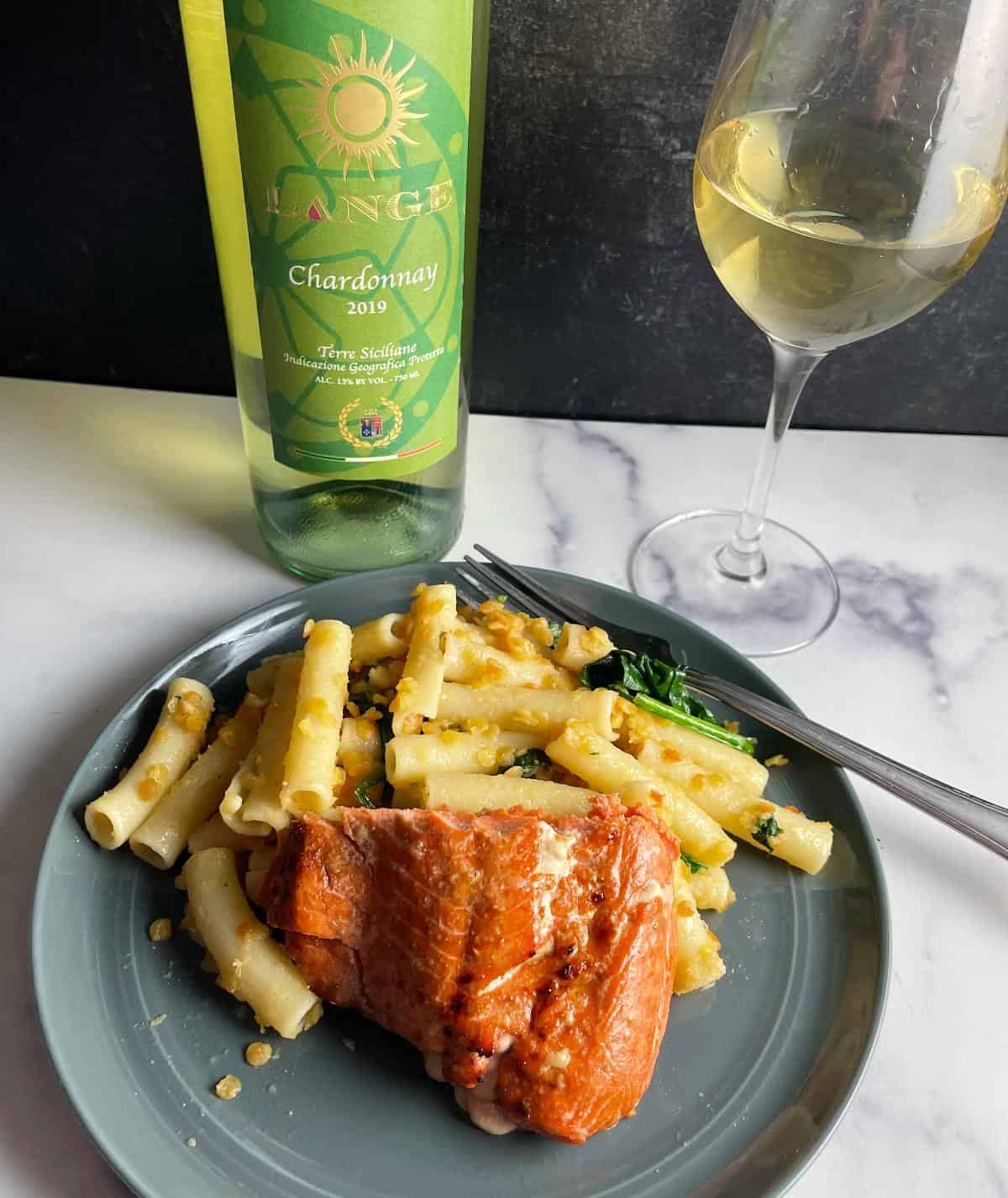 Salmon plated with ziti pasta and served with a bottle and glass of Chardonnay.