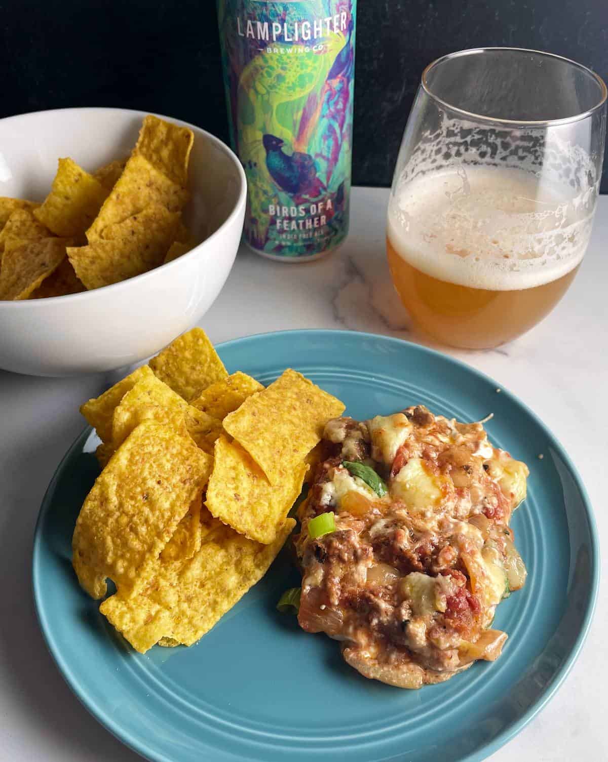 chorizo dip plated with tortilla chips with an IPA beer in the background.