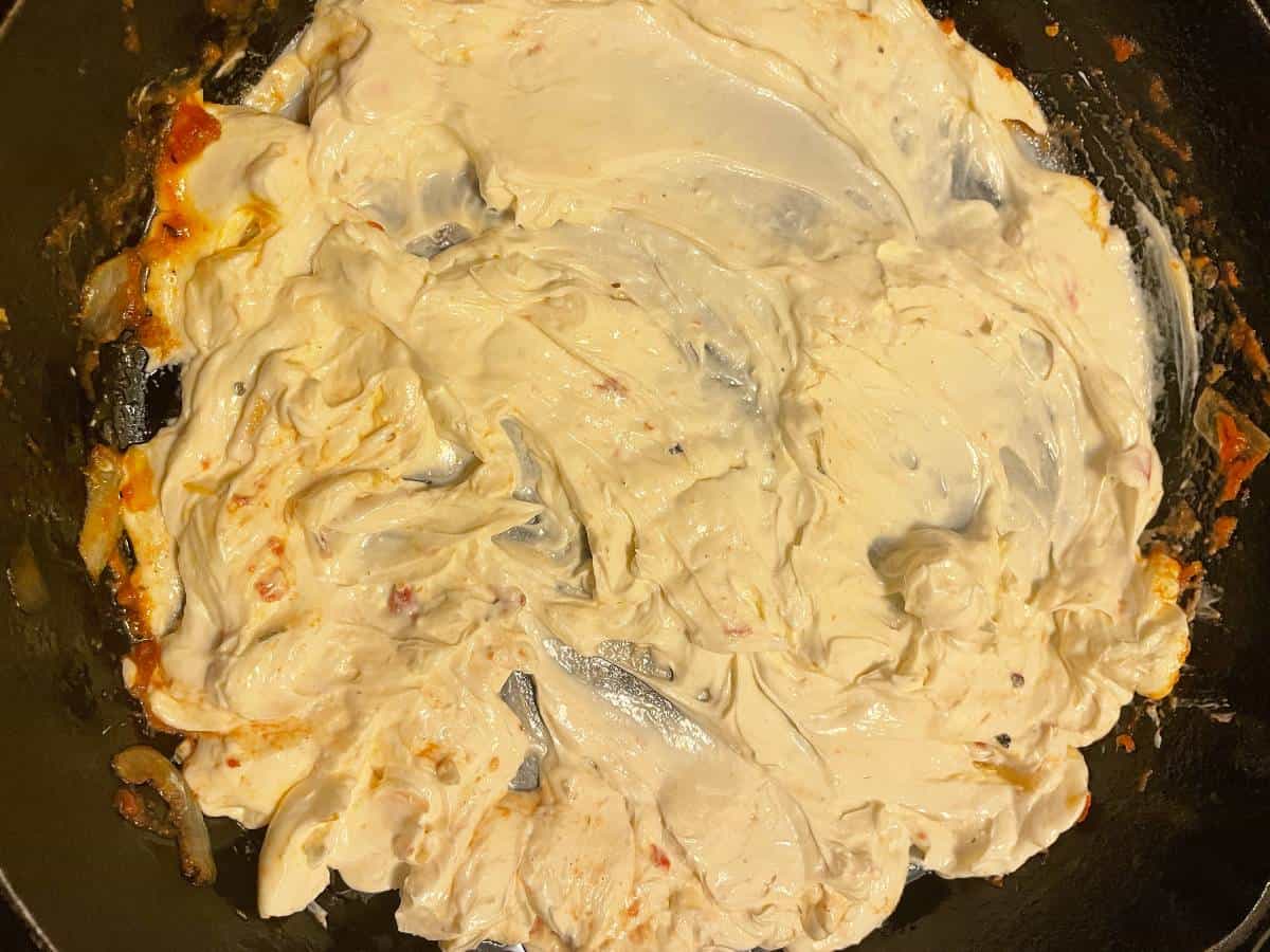 Spreading cream cheese on the bottom of a skillet.