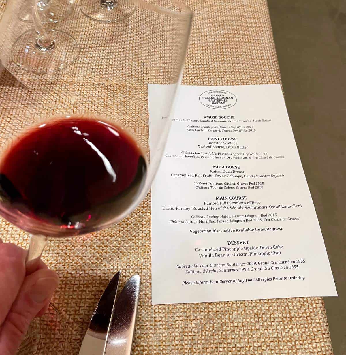 menu for a multi-course Bordeaux wine dinner at Catalyst restaurant, with a glass of red wine to the left of the menu.