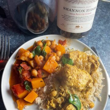 plate with Indian butter chicken along with butternut squash curry, paired with a Petite Sirah wine.