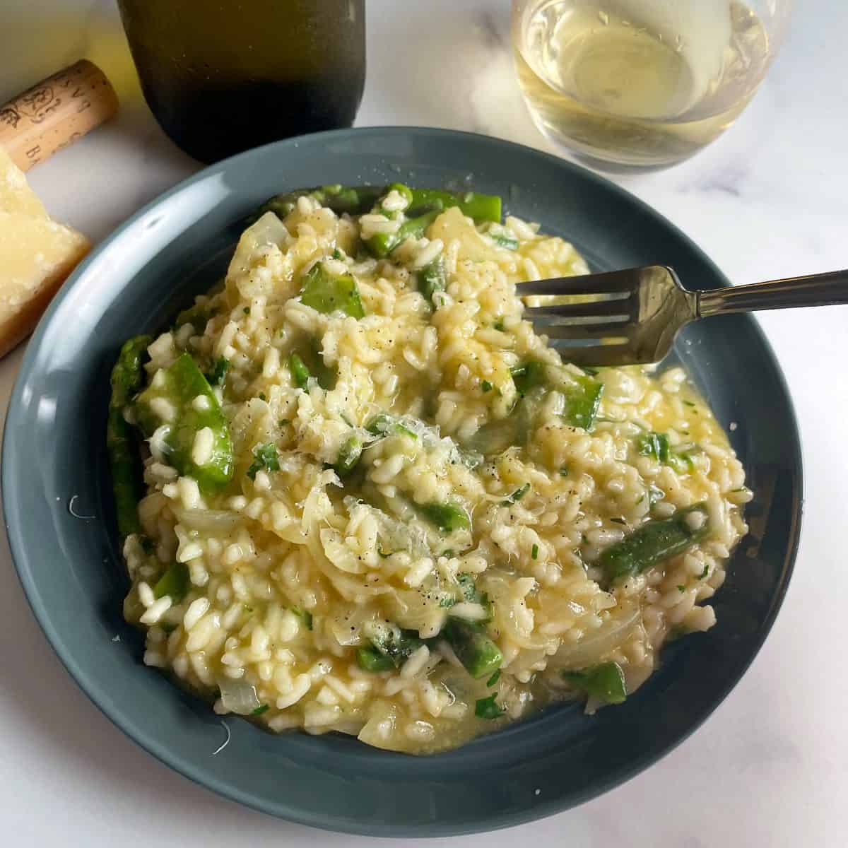 a fork scooping a bite of pea and asparagus risotto.