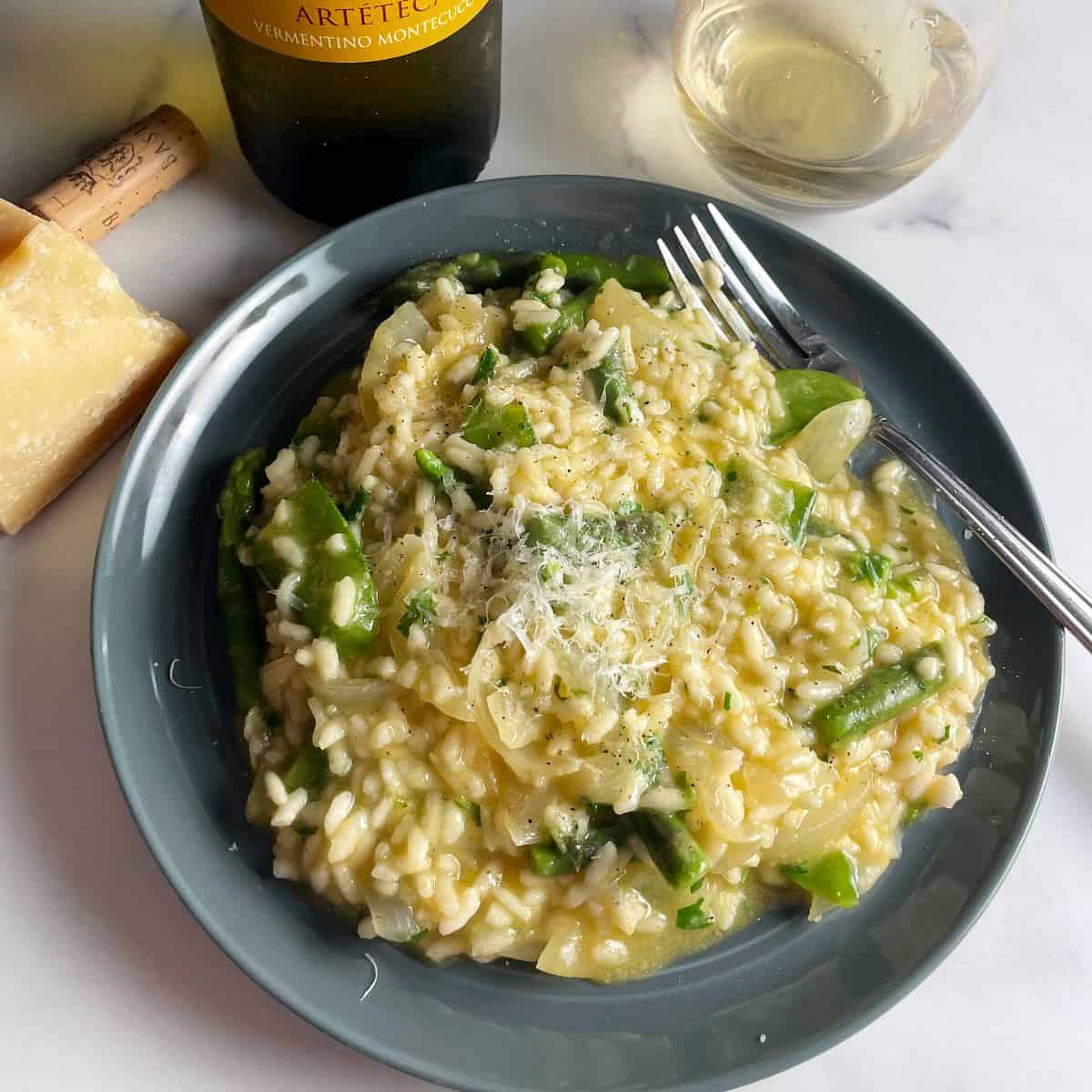 pea and asparagus risotto plated along with Vermentino white wine in the background.