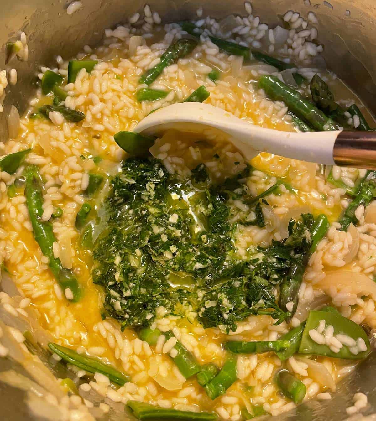 adding pureed herbs to asparagus and pea risotto.