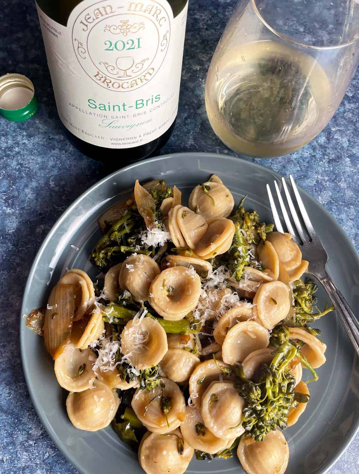 Plate of orechiette pasta with broccolini, served with a white sauvignon blanc wine.