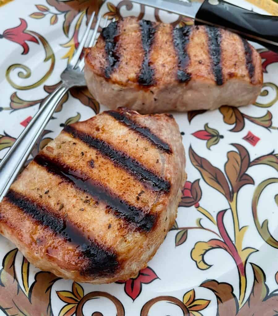 Two grilled pork chops on a platter.