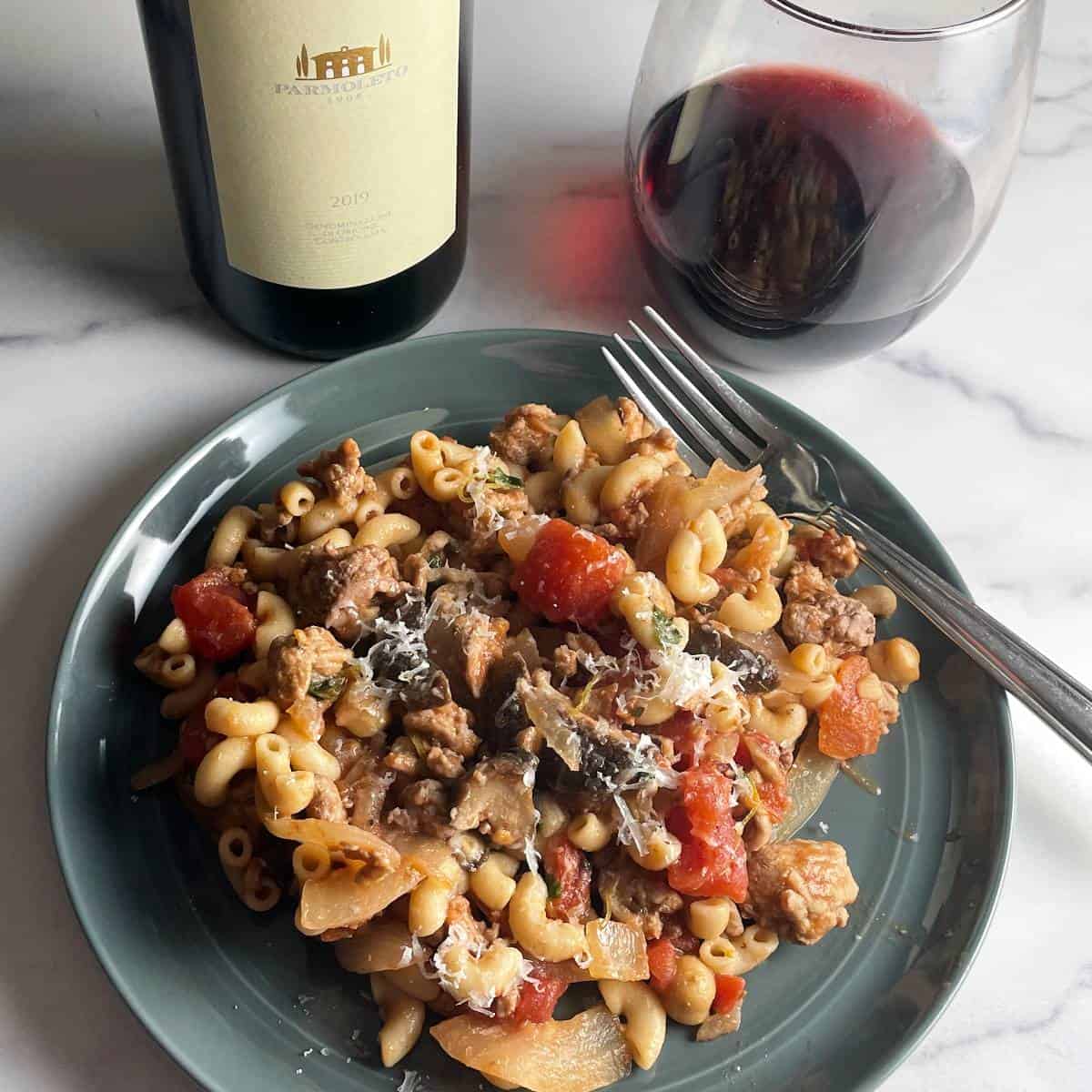 Ground turkey pasta with tomatoes and mushrooms on a gray plate.