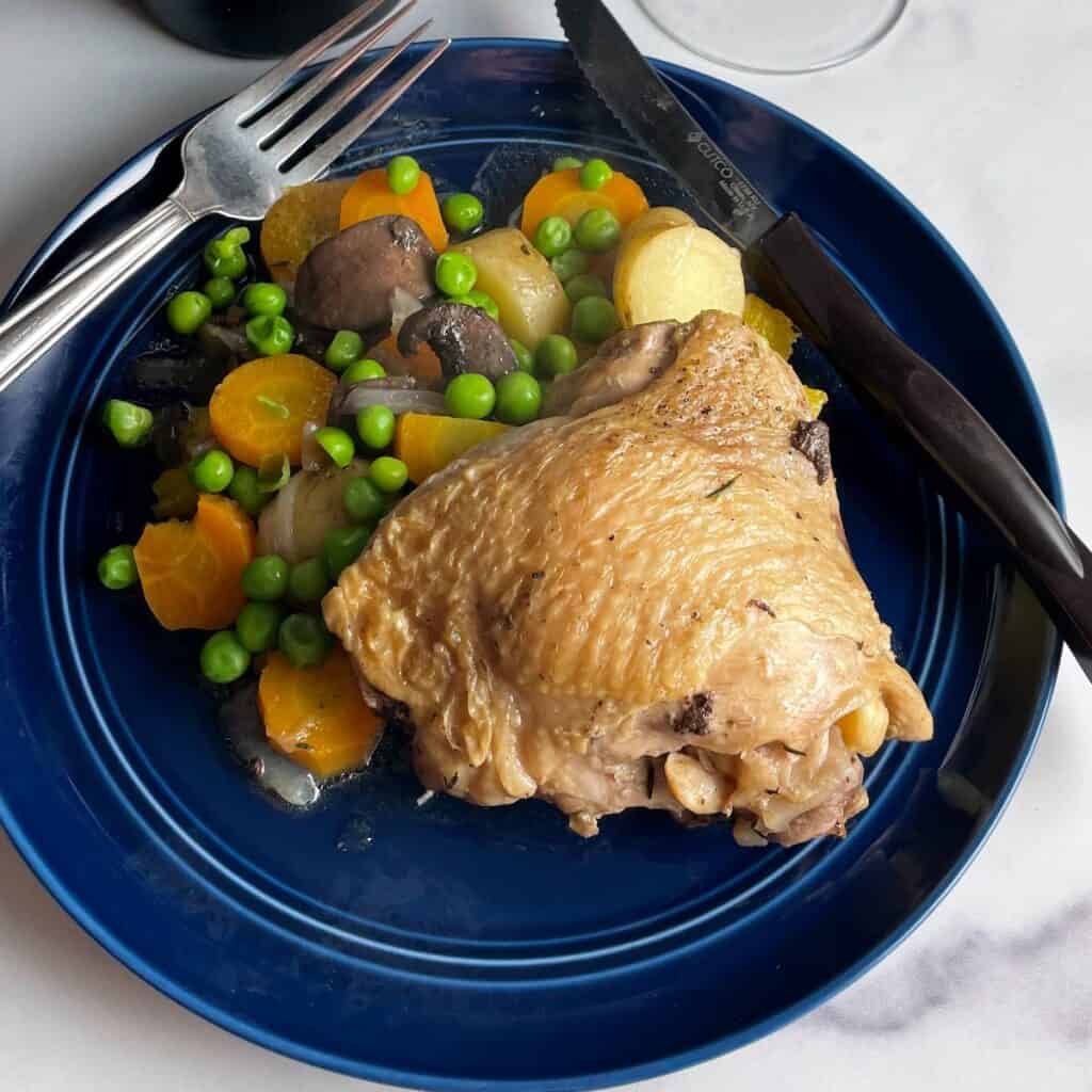 braised chicken thigh plated with vegetables.