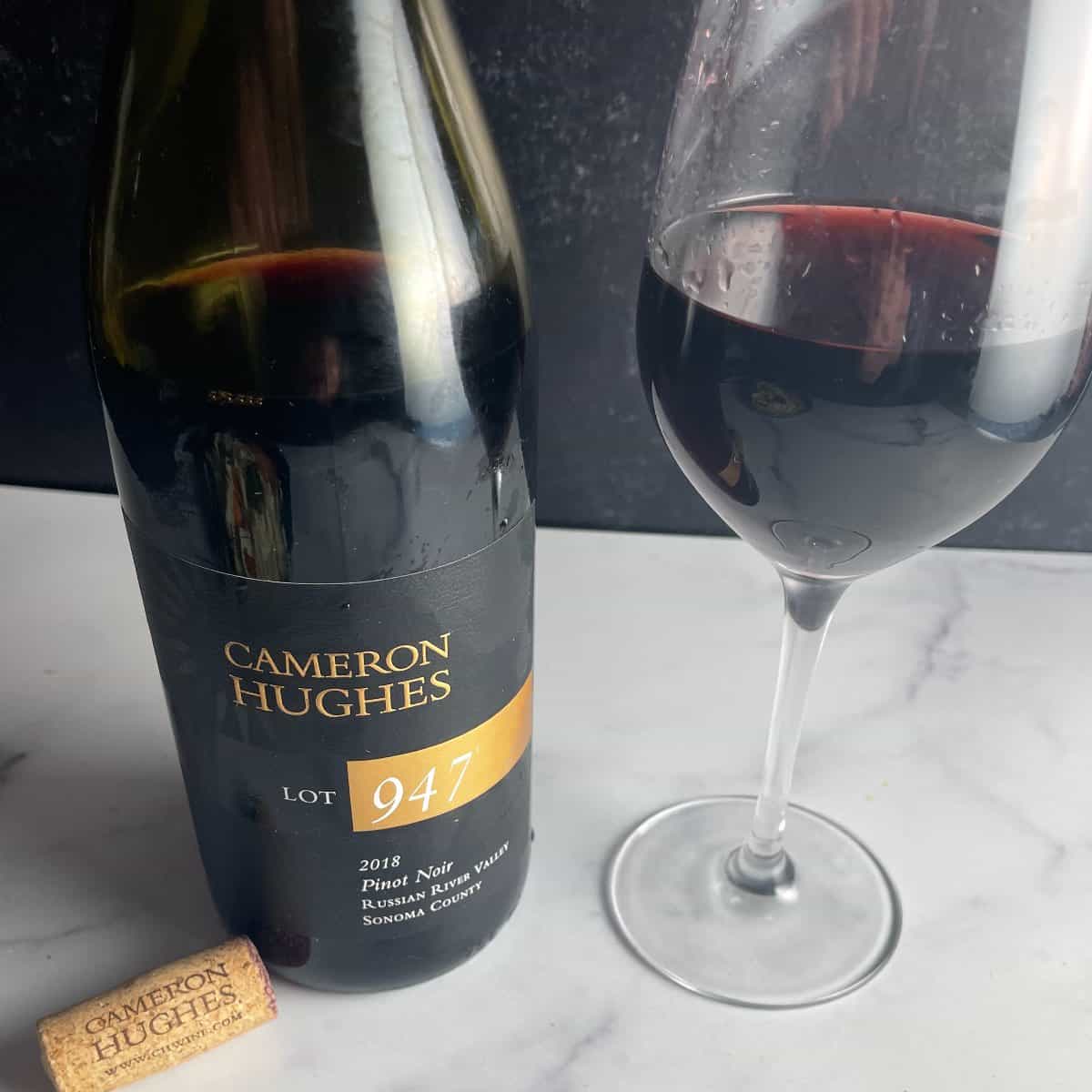 Cameron Hughes Pinot Noir bottle with a glass of the red wine alongside it.