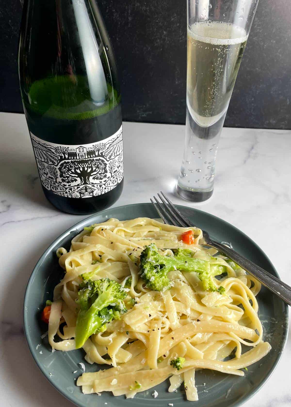 plate of fettccuine primavera served with a bottle and glass of sparkling Picpoul wine.