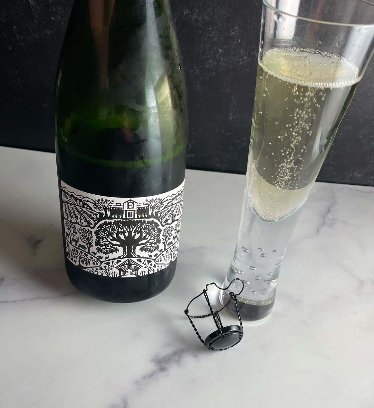 bottle and glass of Halter Ranch Libelle sparkling wine, showing the front of the bottle with a black and white version image of the estate.