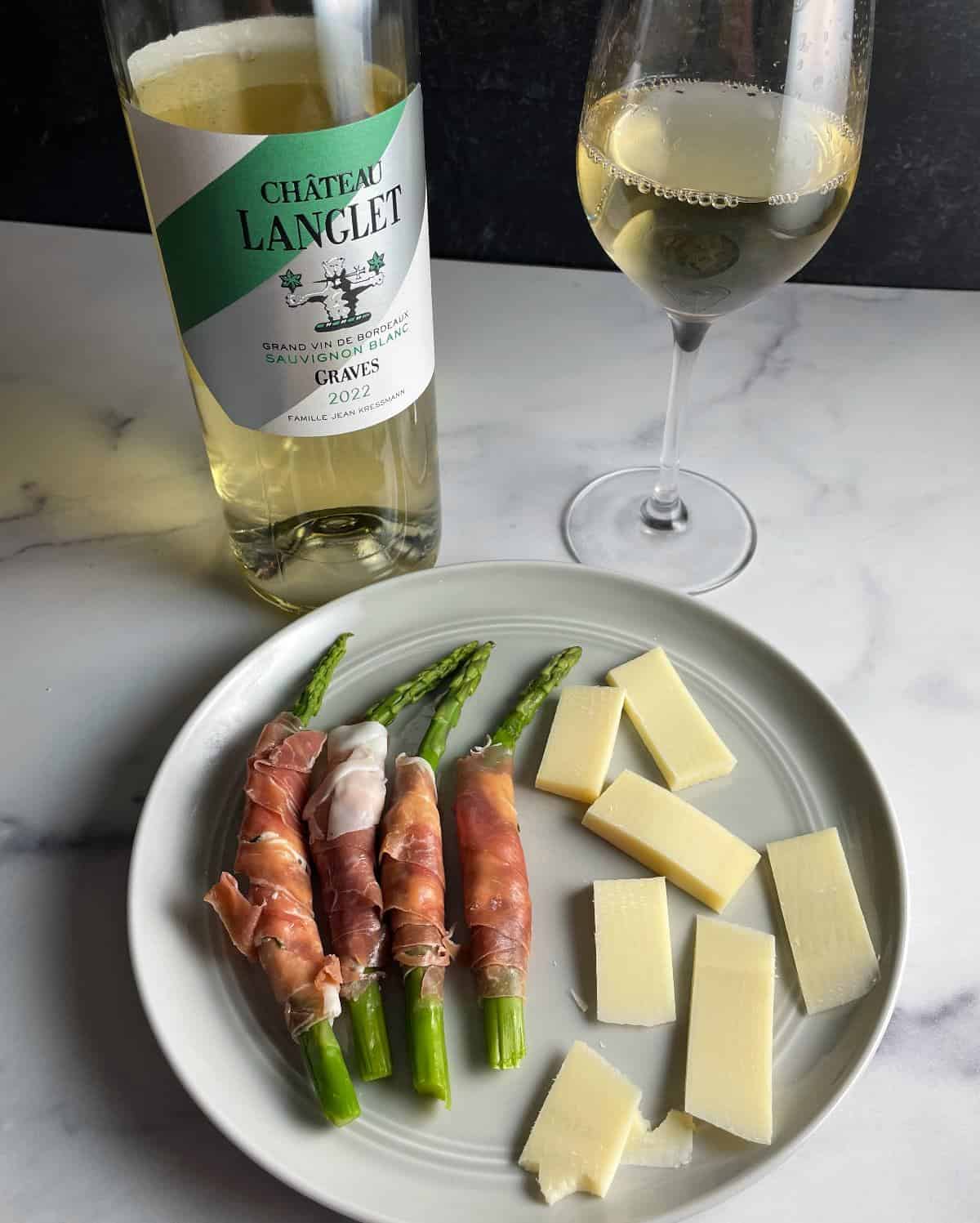 plate with Gruyere cheese and prosciutto wrapped asparagus, paired with a Sauvignon Blanc white wine from Graves, Bordeaux.