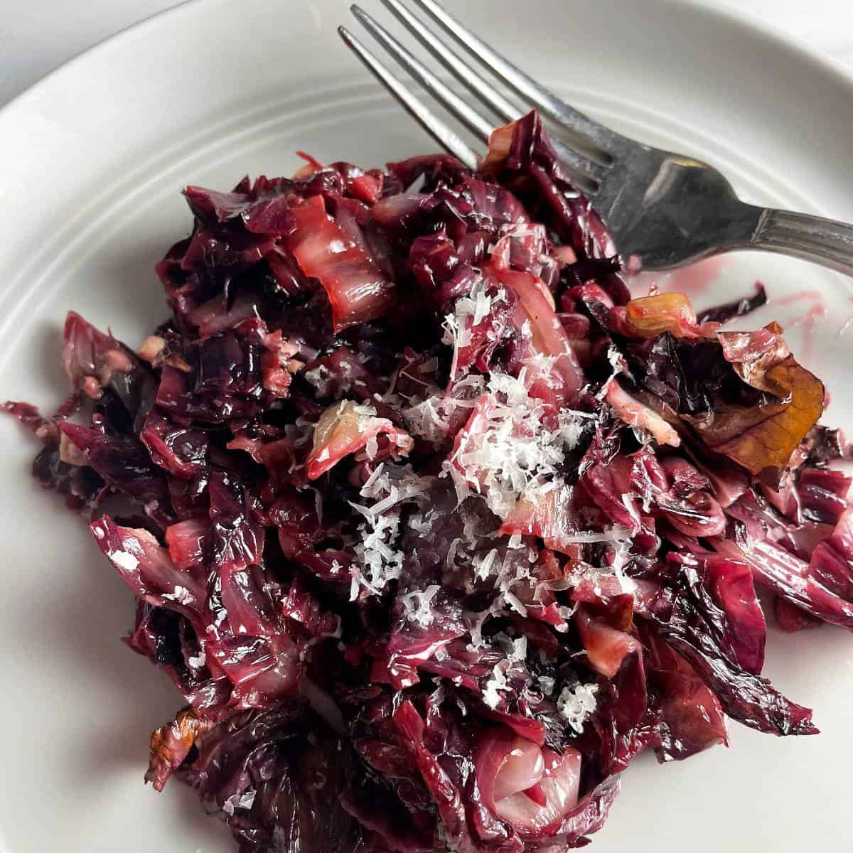 Sautéed radicchio on a plate topped with grated Parmesan cheese.