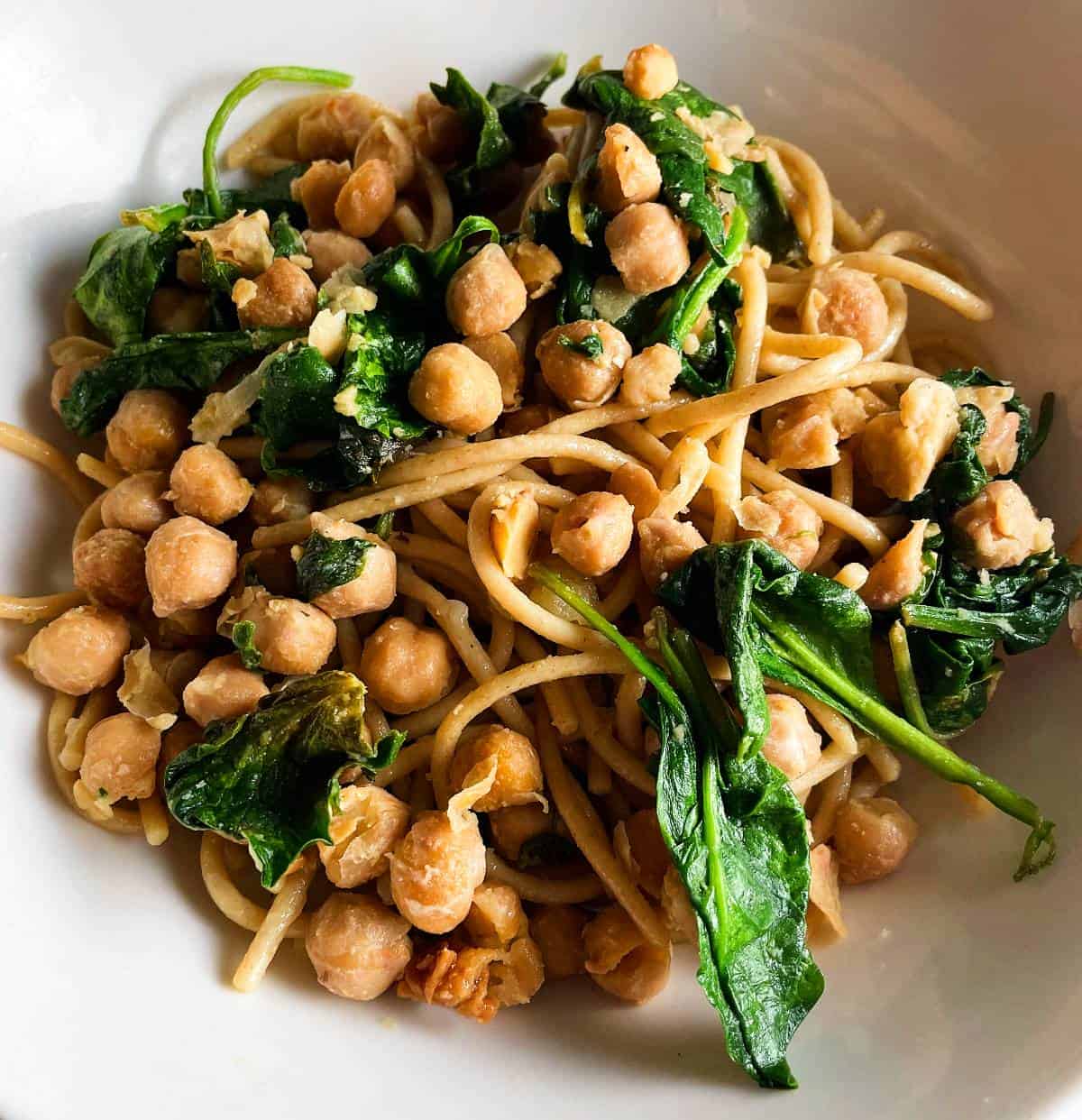 spaghetti with spinach and chickpeas in a bowl.