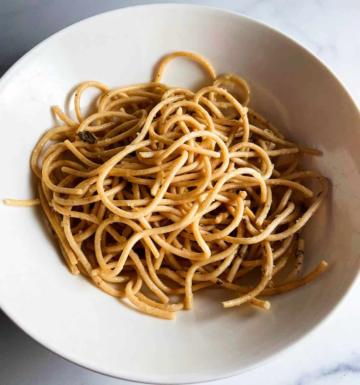 white bowl with plain, cooked spaghetti in it.