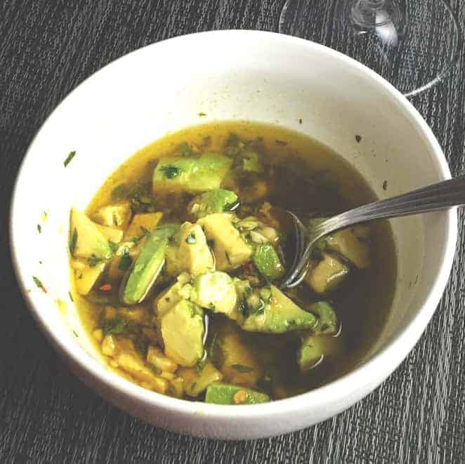 chimichurri sauce in a white bowl with avocados.