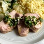 closeup shot of pork tenderloin slices topped with chimichurri.
