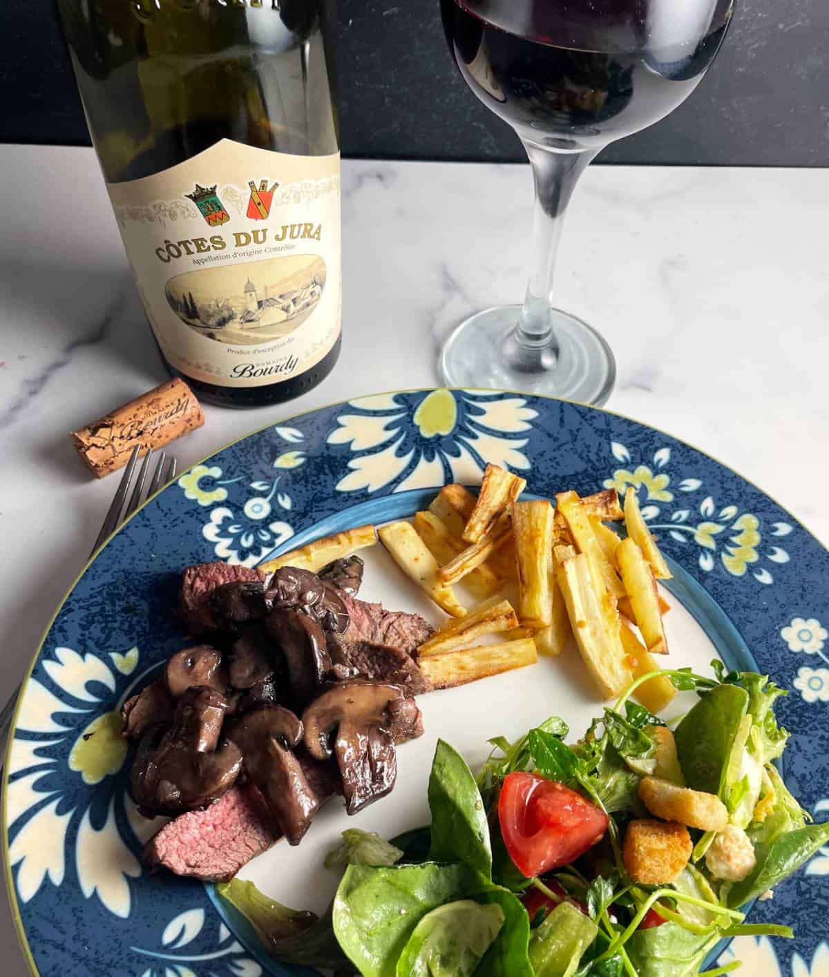 a plate with steak and mushrooms, salad and parsnip fries.