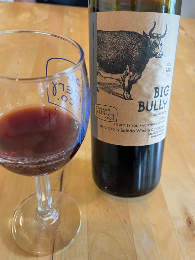 a bottle of Big Bully red wine with a glass of it to the left of the bottle.