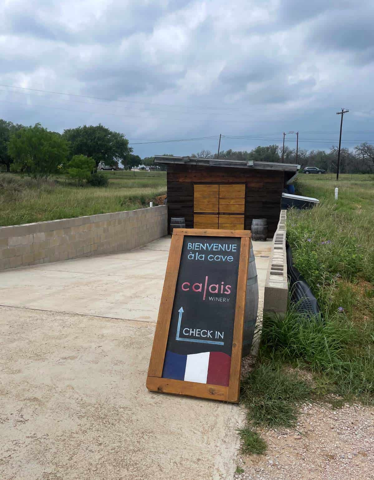 A sign indicating the entrance to Calais wine cave. Gray clouds in the background.