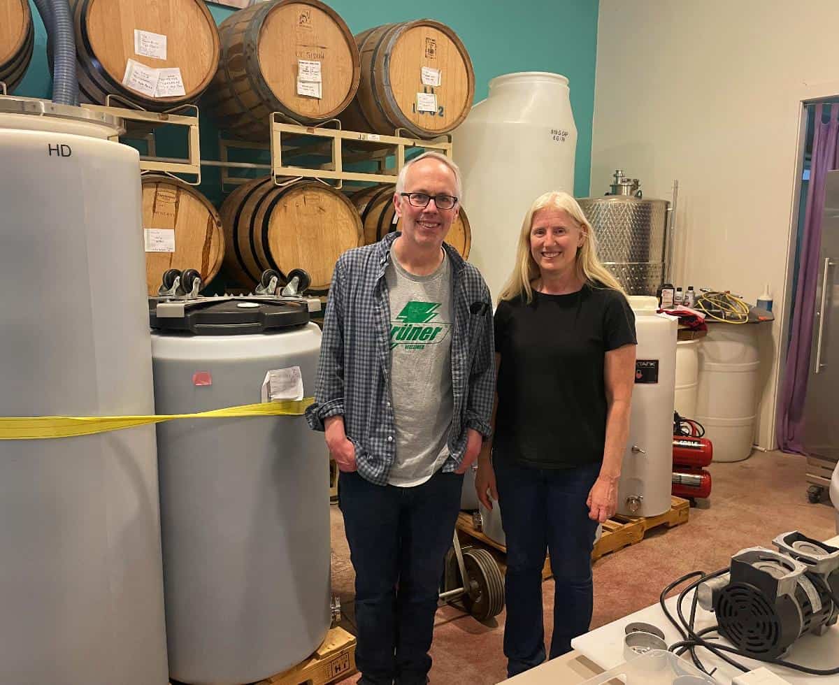 Salado Winery Owner / Winemaker June Ritterbusch with David Crowley, posing by wine tanks.