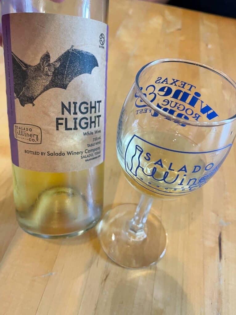 a bottle of Night Flight white wine with a glass of it to the right of the bottle.