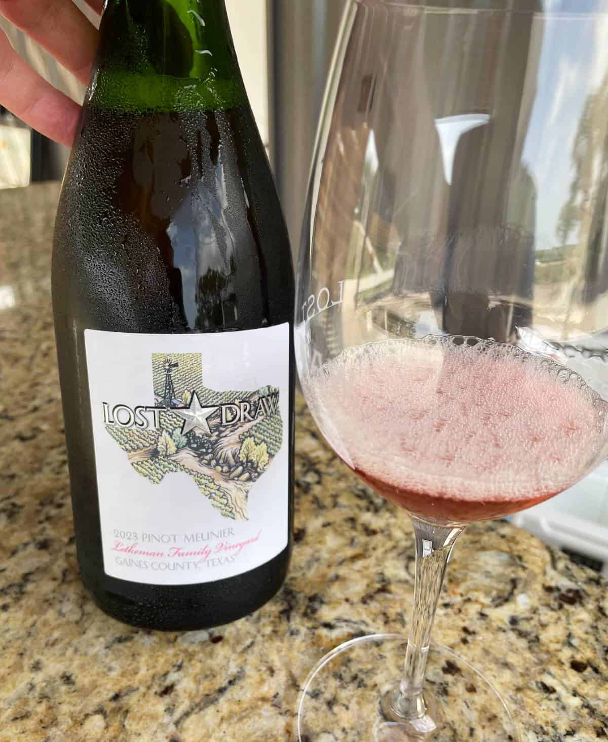 a bottle and glass of sparkling rosé wine at Lost Draw winery in Texas.