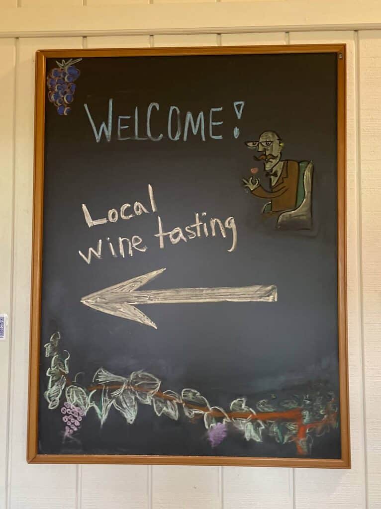 A chalkboard sign that says Welcome! Local wine tasting.