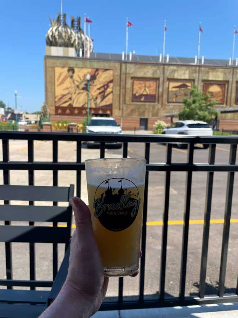 holding a pint of beer with a view of the Corn Palace in the background.