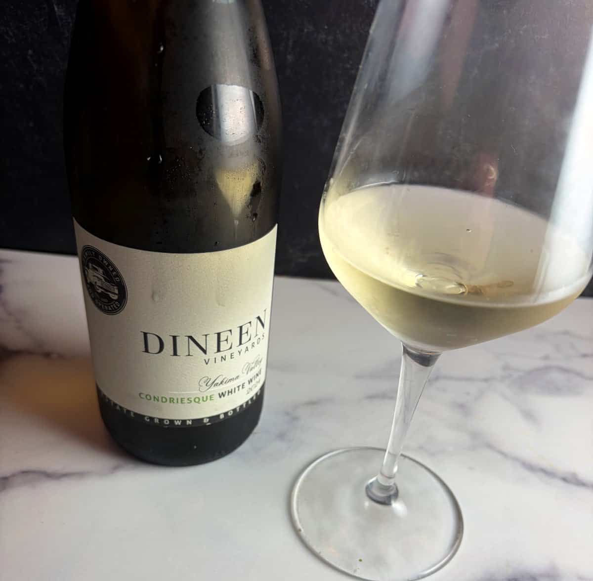 A bottle of Dineen Condriesque white wine with a glass of it next to the bottle.