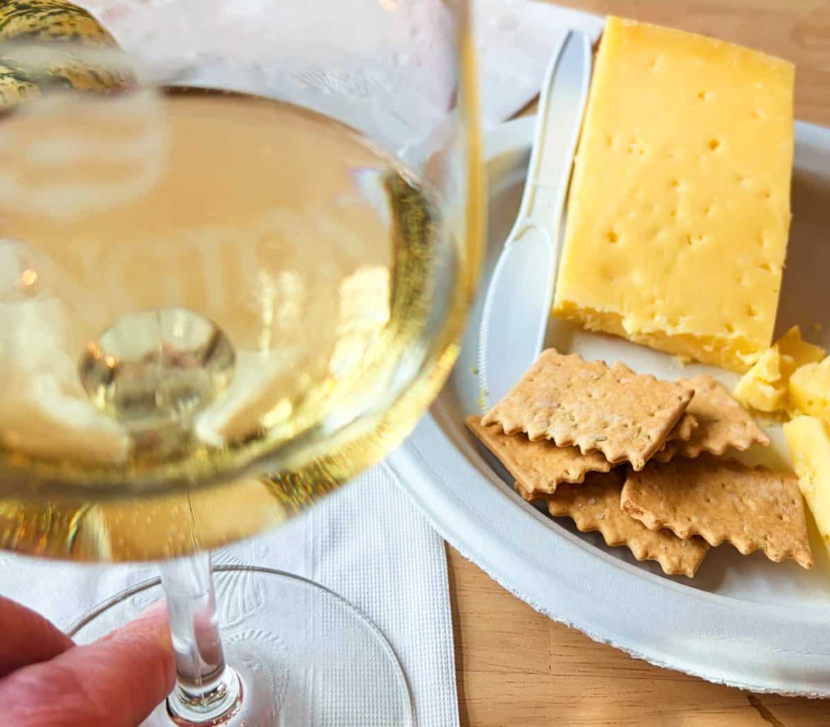 closeup of a glass of Chardonnay served with a plate of cheese and crackers.