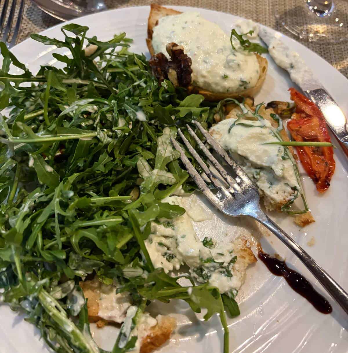 arguula salad plated with toasts topped with ricotta.